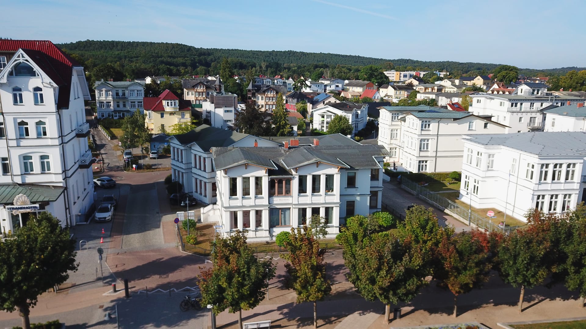 Haus Meerblick hinter der Baumreihe der Promenade von Ahlbeck, dahinter Villen und Küstenwald