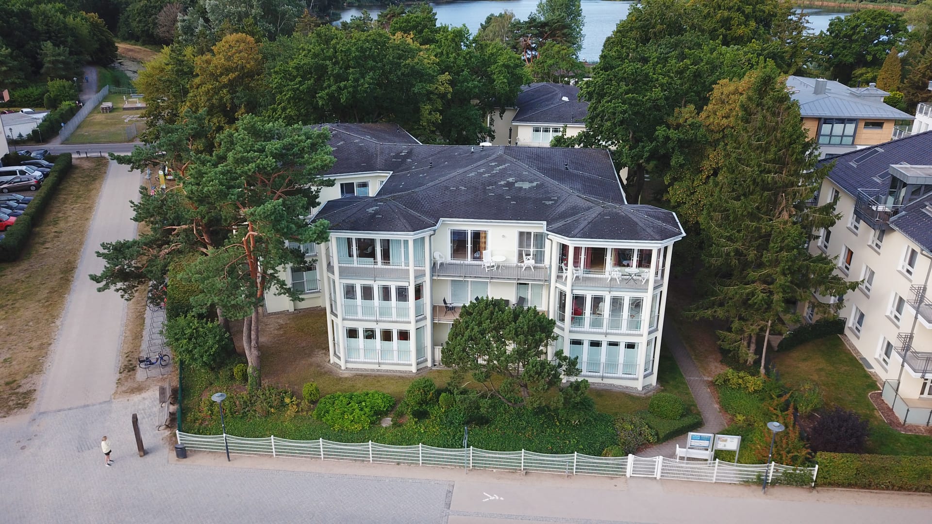 Luftaufnahme des Hauses Strandoase in Heringsdorf – weiße Villa mit verglasten Balkonen in erster Reihe hinter der Düne