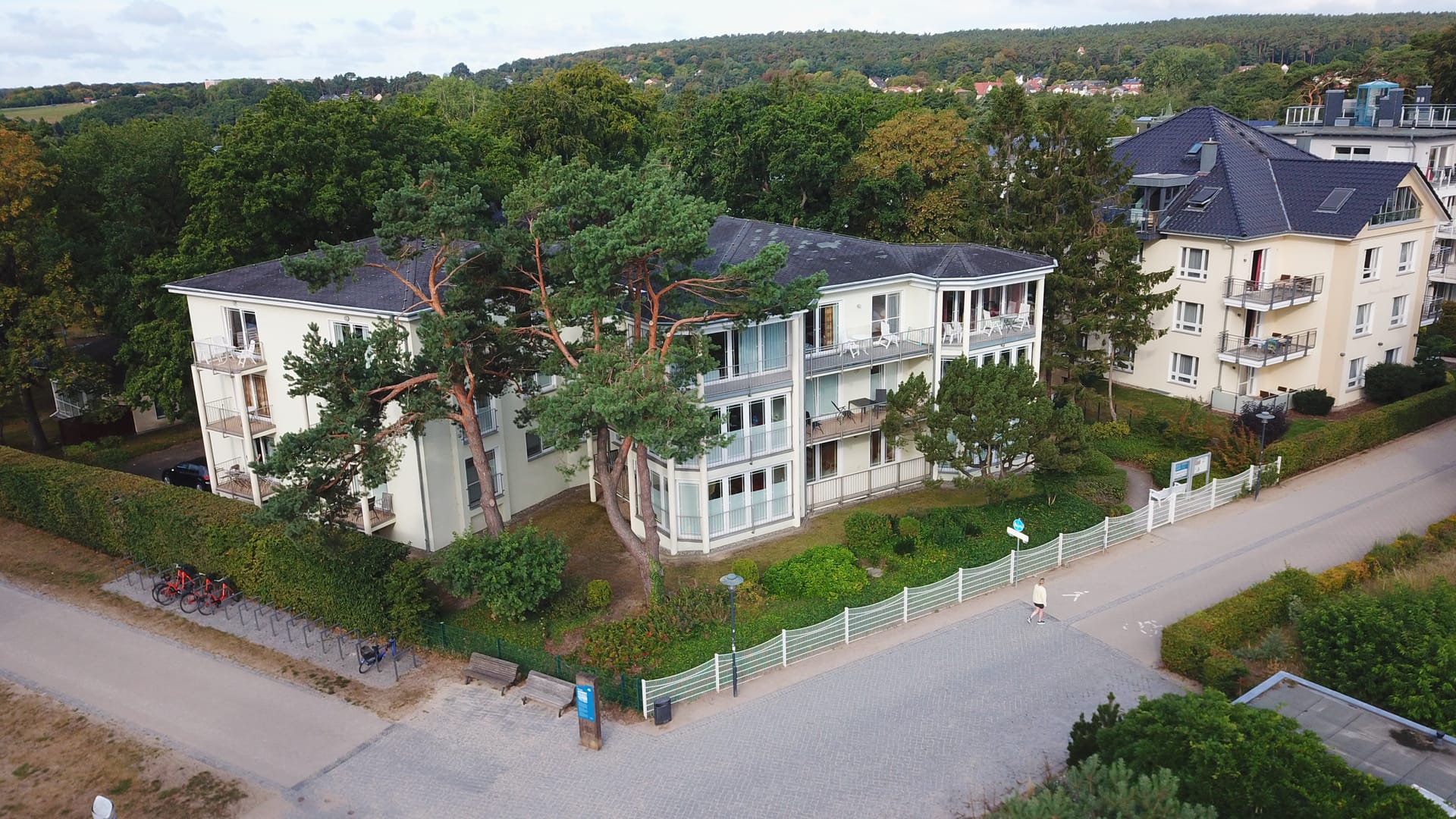 Seitliche Luftaufnahme des Hauses Strandoase Heringsdorf zwischen alten Kiefern, dahinter das Villenviertel des Seebads