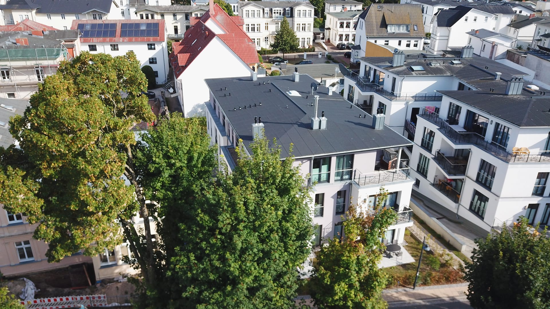 Seitlicher Blick auf das Appartementhaus Quartier 6 in Ahlbeck mit altem Baumbestand