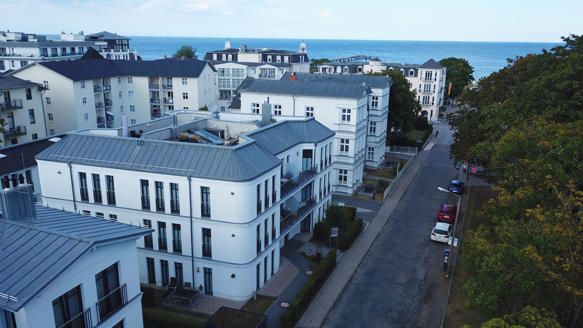 Luftbild vom Quartier am Kurpark Ahlbeck mit Dachterrasse, Kurpark-Bäumen und Ostsee am Horizont