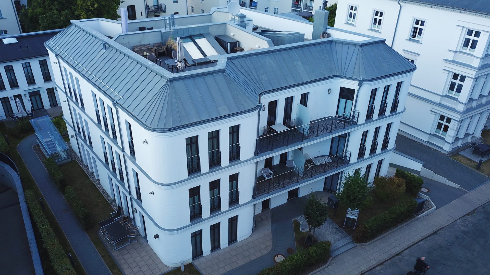 Straßenecke des Quartiers am Kurpark Ahlbeck mit gerundeter Fassade und Möblierung auf der Dachterrasse
