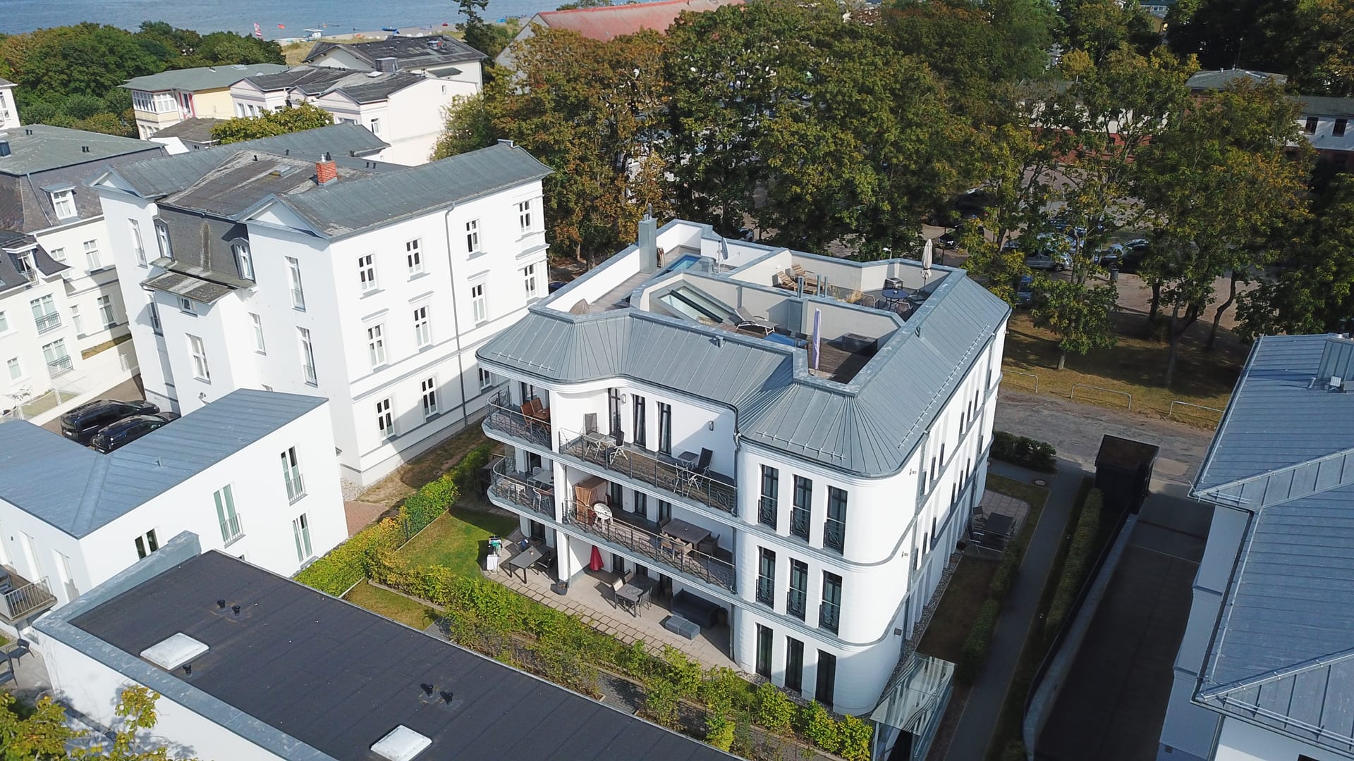Gartenseite des Quartiers am Kurpark Ahlbeck in der Sonne, Balkone und Terrassen, links hinten die Ostsee