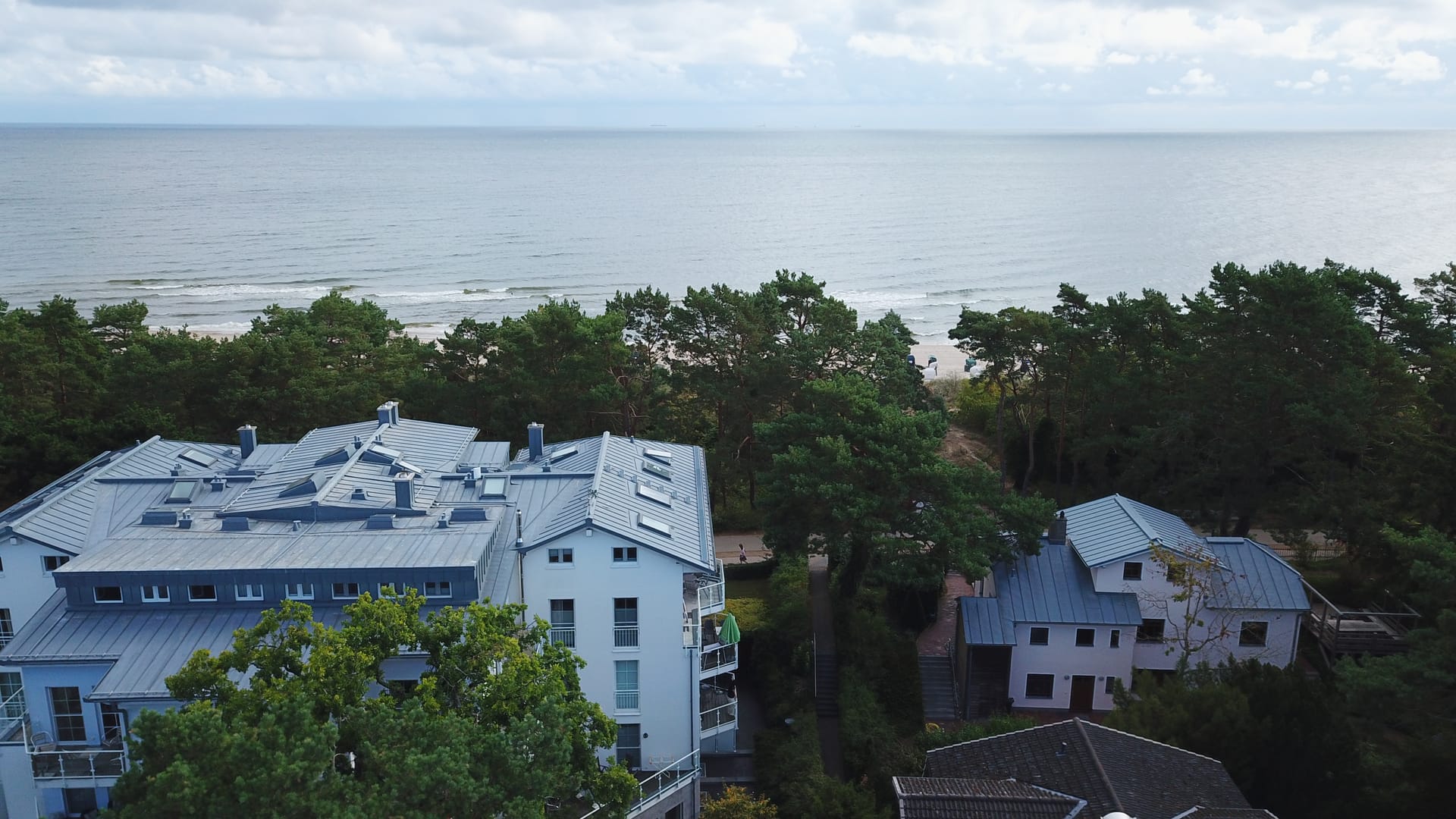 Blick über den bewaldeten Dünenstreifen an der Maxim-Gorki-Straße auf Strand und offene Ostsee vor Heringsdorf