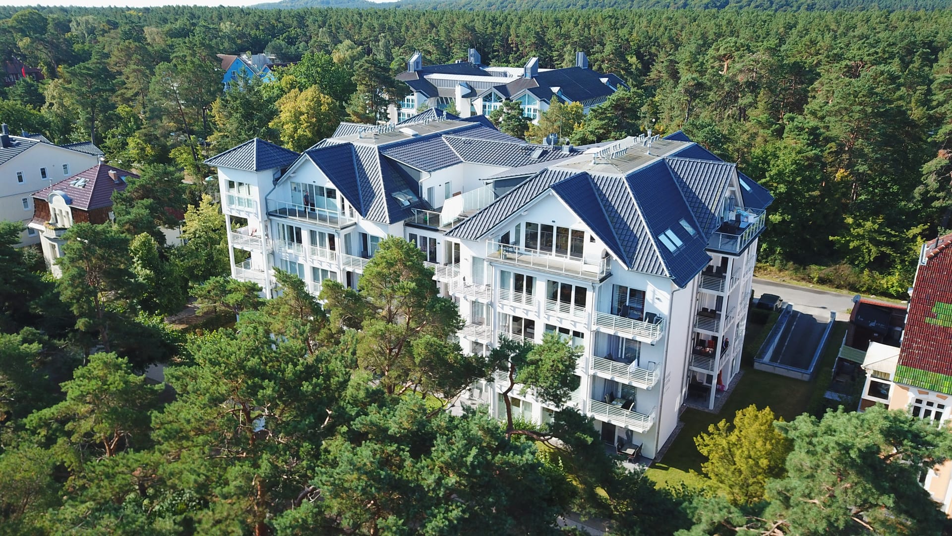 Strandresidenz Else Marie Ahlbeck aus der Luft – Balkonfassade und Giebel über den Dünenkiefern