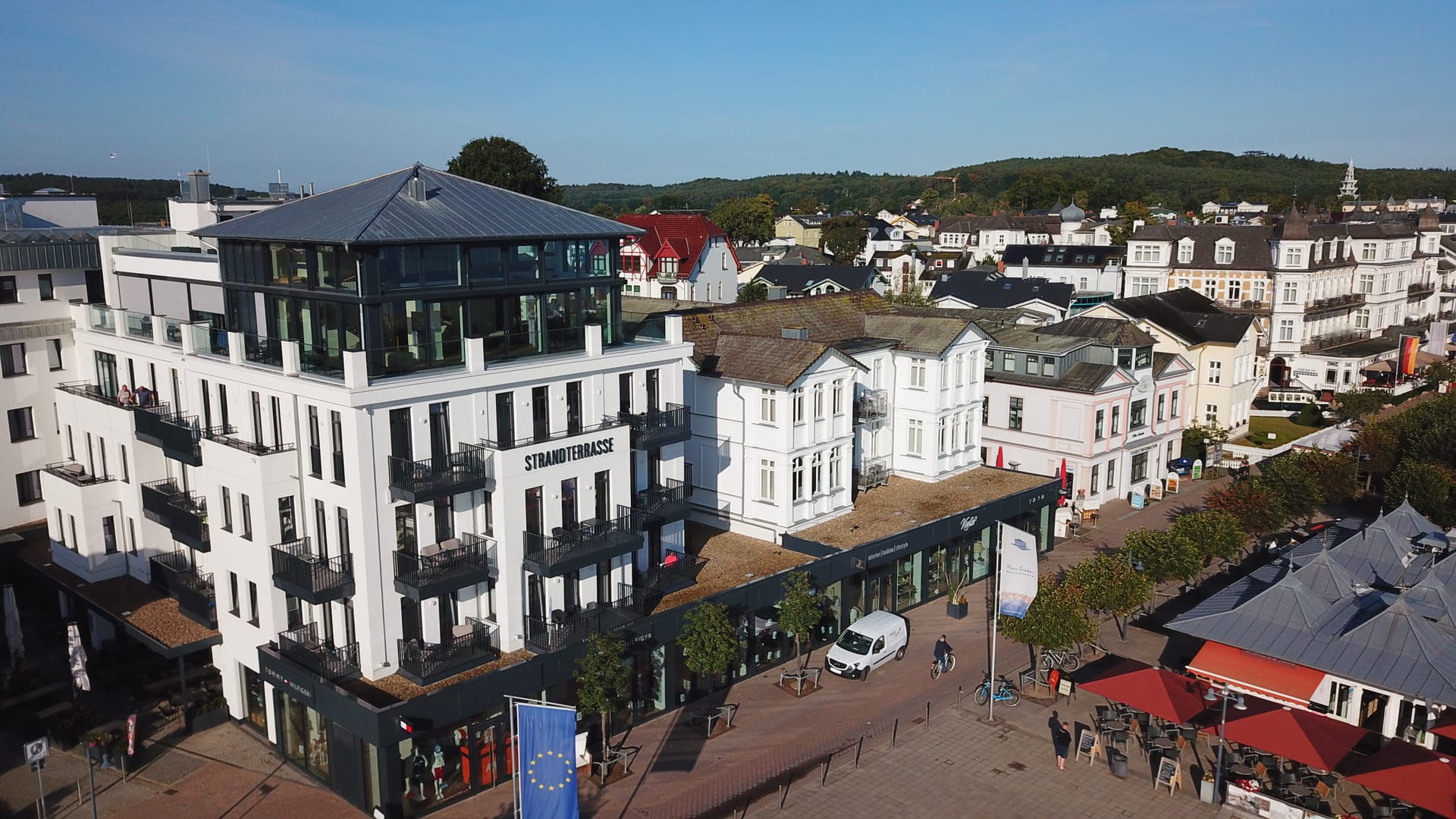 Nahaufnahme der Strandterrasse Ahlbeck mit verglastem Dachgeschoss, im Hintergrund die Bäderarchitektur des Seebads