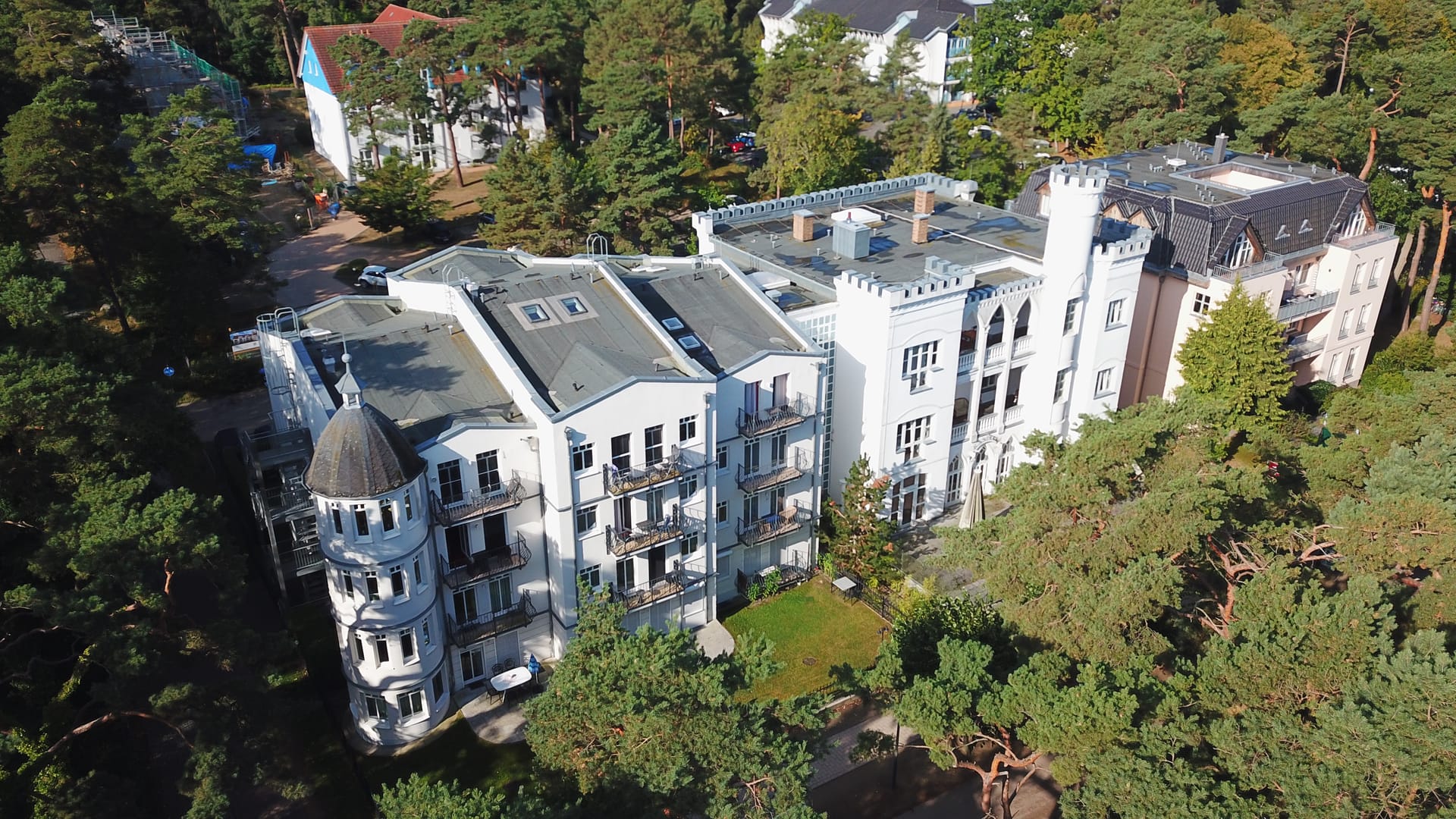 Gartenseite der Appartement-Suiten Tannenburg Ahlbeck mit rundem Eckturm und Balkonen