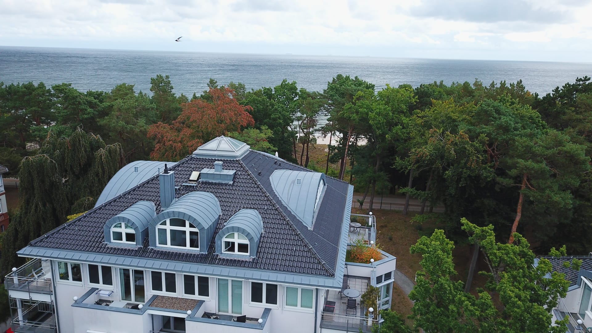 Dach der Villa Darja Heringsdorf mit Rundgauben, dahinter die offene Ostsee hinter der Düne