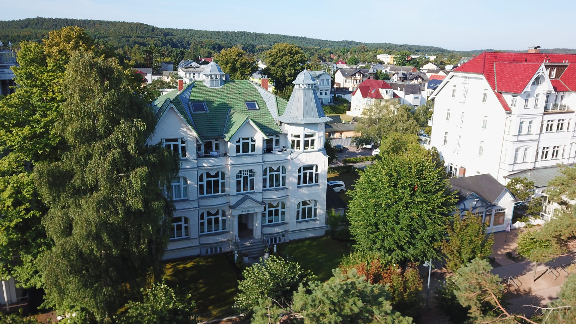 Seitliche Drohnenaufnahme der Villa Germania Ahlbeck mit grünem Ziegeldach und Türmchen