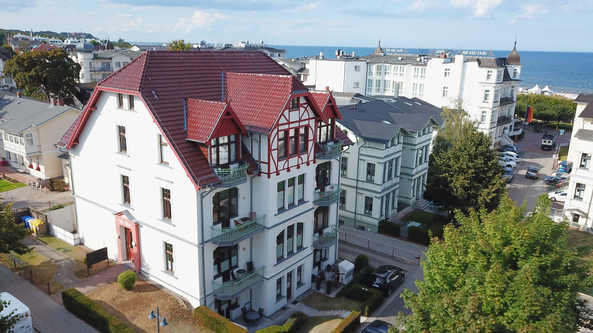 Luftaufnahme der Villa Medici Ahlbeck – denkmalgeschützte Jugendstil-Villa mit rotem Fachwerkgiebel, im Hintergrund die Ostsee