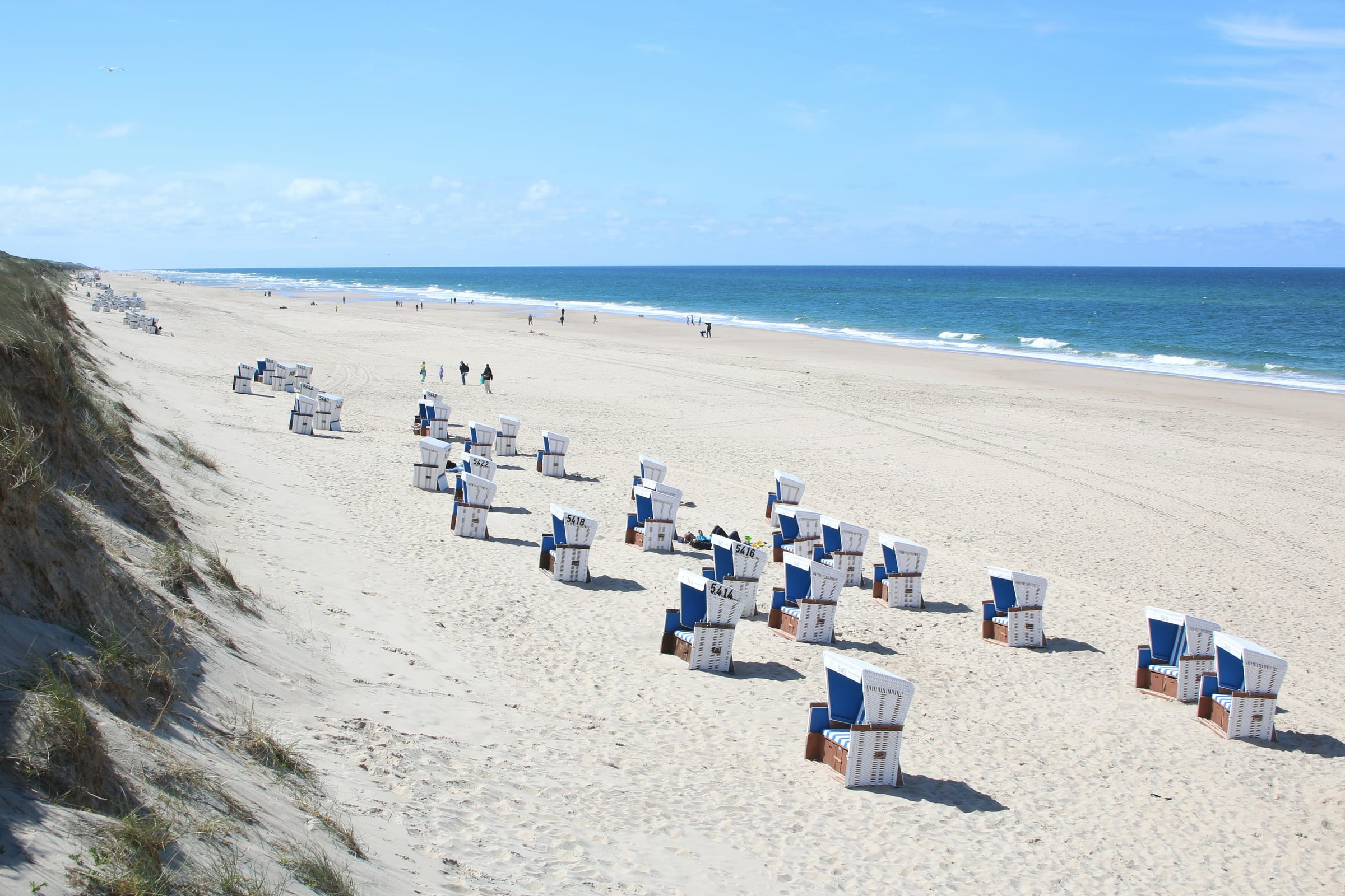Weiter, feiner Sandstrand mit Strandkörben und Dünenkante